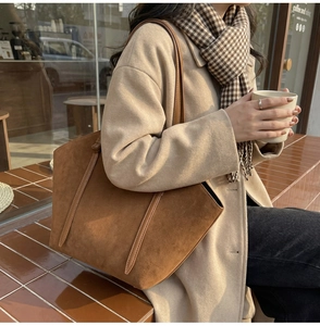 Detail of caramel suede tote bag with leather straps in an outdoor cafe setting