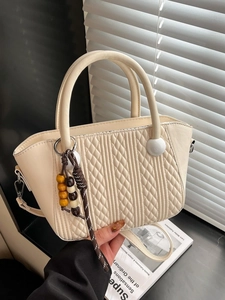 Minimalist cream woven bucket bag with quilted patterns and wooden bead charm accessory