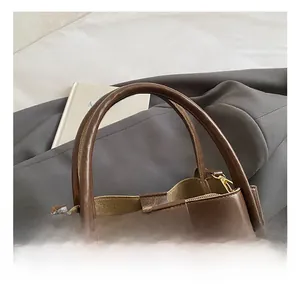 Close-up of deep brown leather handbag with reinforced handle and gold metal hardware