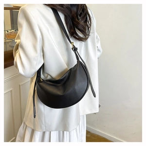 Macro detail of black litchi grain leather texture and golden hardware on crossbody bag