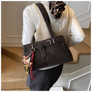 Détail du sac à bandoulière rétro marron foncé avec boucle en métal et breloque ours