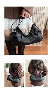 Detail of black pleated faux leather shoulder bag showing vertical ripple texture and strap