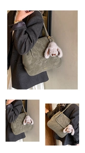 Détail du sac seau en cuir vert foncé avec un joli pendentif de lapin en peluche