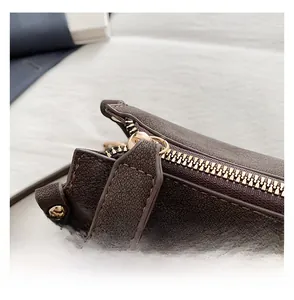 Detailed close-up of smooth gold-tone zipper on brown textured leather crossbody bag