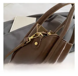 Detailed close-up of premium gold hardware and brown textured leather on handbag