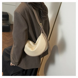 Detail of beige litchi grain leather crescent bag with adjustable brown shoulder strap