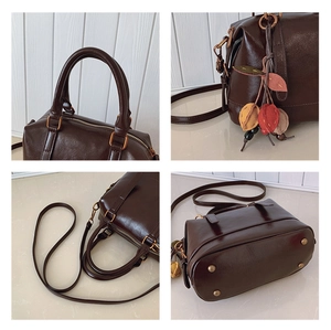Detailansicht der braunen Boston-Tasche aus Ölwachsleder mit Blattanhänger und Metallfüßen