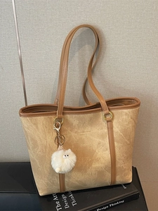 Stylish khaki suede tote bag with brown handles and a white fluffy pompom keychain