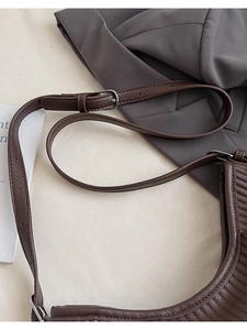 Detail of dark brown tote bag with vertical embossed stripes and silver buckle strap