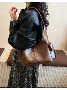 Detailed side view of brown vintage leather shoulder bag with functional side pocket flap