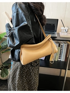 Dettaglio di una borsa a spalla color albicocca con apertura a pieghe e finitura lucida