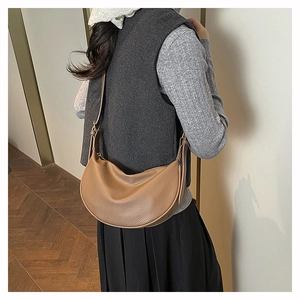 Detailed back view of a brown pebbled leather half-moon crossbody bag worn by a model