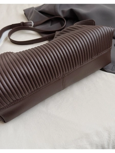 Close-up of deep brown tote bag featuring textured horizontal pleats and fine stitching