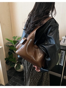Detail view of brown oil wax leather shoulder bag with side flap pocket worn by a model