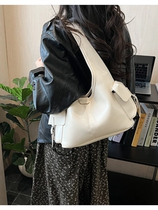 Detail view of large cream PU leather hobo bag with side utility pockets shown on shoulder