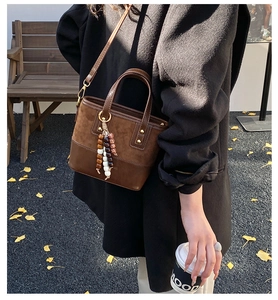 Detail of dark brown vintage bucket bag with colorful wood beads on model in winter