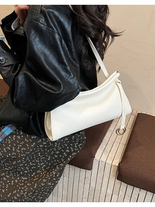 Vista laterale dettagliata di una borsa baguette in pelle bianca con frange e anelli