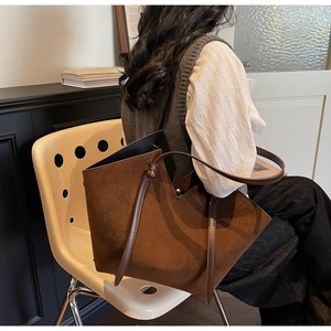 Detail of a brown suede tote bag with V-cut design and knotted shoulder straps