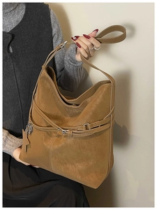 Détail du sac cabas en daim camel montrant la boucle de ceinture et le pendentif