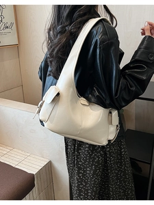 Creamy white leather shoulder bag with side flap pocket worn with a black leather jacket
