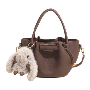 Dark brown lychee pattern leather bucket bag with a plush rabbit charm and gold hardware