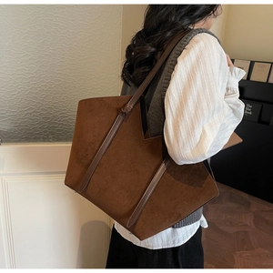 Detail of a large brown suede tote bag with V-cut design and stylish shoulder knot accents
