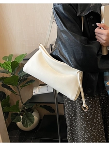 Dettaglio della trama in pelle bianco crema e degli anelli dorati sulla borsa baguette