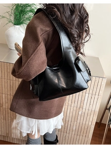 Detail of black vintage leather tote bag showing side flap pocket and shiny texture