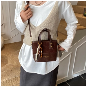 Detail of retro brown crossbody bag with wooden bead charm and fashion text print