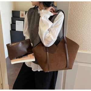 Detail of dark brown suede tote bag with V-shaped opening and matching mini clutch bag