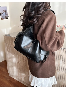 Detail of a large black vintage faux leather tote bag worn as a stylish shoulder bag