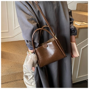 Detail of dark brown leather handbag with plush ball pendant and long shoulder strap