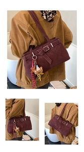 Détail du sac à bandoulière bordeaux mat avec boucles de ceinture et pompon à carreaux