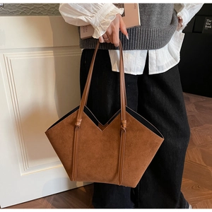 Detail of dark brown tote bag with V-shaped cut and suede texture in lifestyle setting