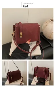 Detail view of burgundy rectangular crossbody bag with golden metal clasp and suede texture