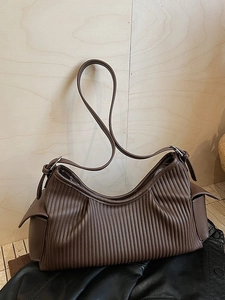 Large capacity dark brown pleated shoulder bag on black leather jacket and wooden floor