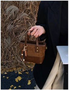 Detail of a leopard brown mini handbag with suede texture, gold studs and wooden beads