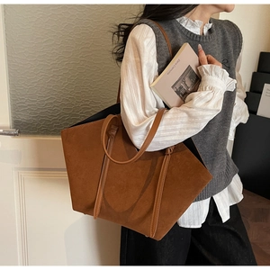 Brown suede tote bag with leather handles shown in a lifestyle shoulder carry view