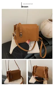 Detail view of brown faux suede crossbody bag with gold rivets and metallic buckle strap