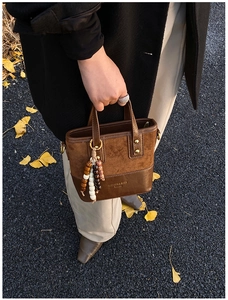 Detail of a leopard print brown patchwork handbag with wooden beads and autumn leaves