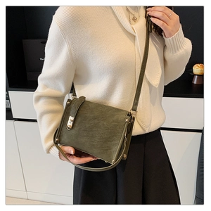 Gros plan d'un sac carré vert foncé rétro en cuir mat avec boucle et détails dorés