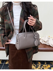 Detailansicht der taupefarbenen Boston Bag aus Leder mit Blatt-Anhänger und Markenlogo