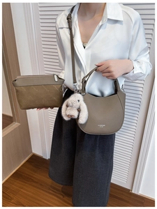 Detail of tan pebble leather shoulder bag with plush bunny charm and monogram clutch bag