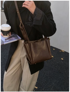Nahaufnahme einer dunkelbraunen Leder-Eimertasche mit Metallfüßen im trendigen Streetstyle