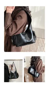 Detail of black leather shoulder bag showing side pocket and metal buckle texture