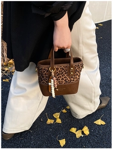 Detail of leopard print tote with brown leather trim and colorful beaded charm