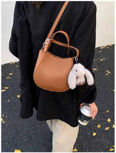 Brown litchi leather crescent crossbody bag shown with chic street style outfit