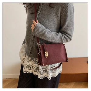 Détail du sac bandoulière en daim bordeaux avec fermoir doré et fine bandoulière en cuir