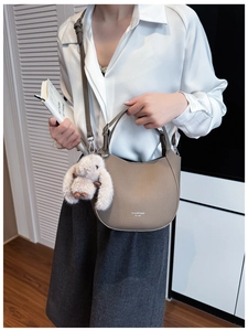 Detail of brown lychee grain leather hobo bag with a plush white bunny charm