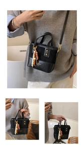 Detail of black bucket bag featuring mixed leather textures and colorful wooden bead charm
